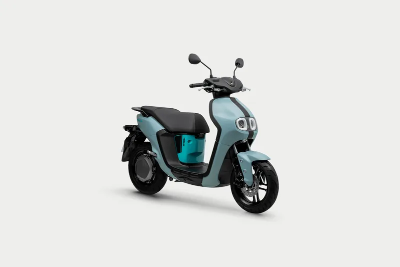 Foto oficial Yamaha: scooter elétrica NEO'S Connected azul fosca, em três quartos de frente, sobre fundo cinza-claro.